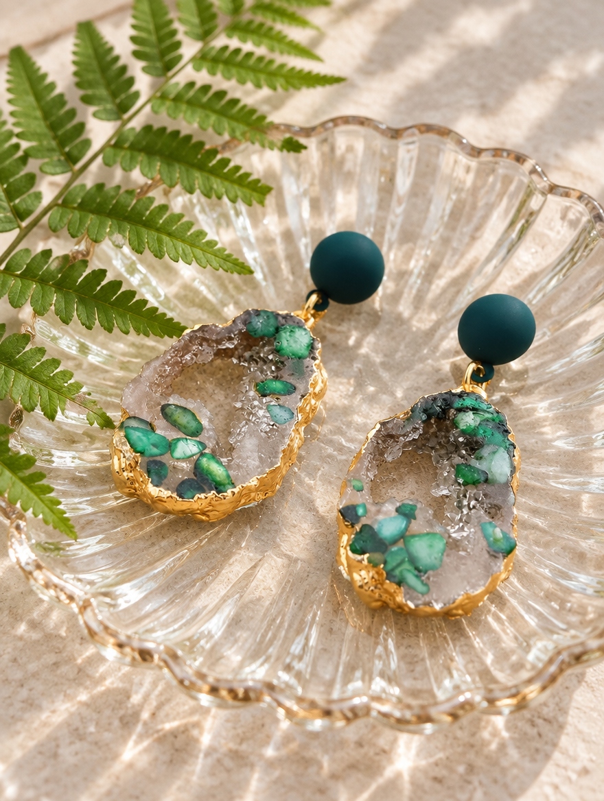 Green stone-look drop earrings with gold-tone edge in a styled still life with props