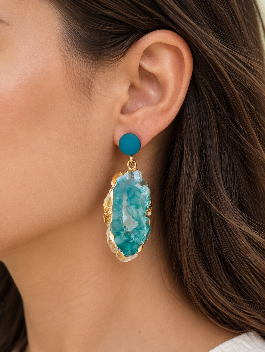 Woman wearing a teal stone-look drop earring with gold-tone edge