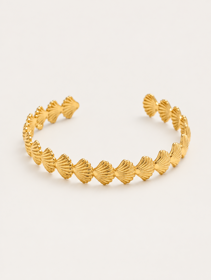 Gold scallop shell open cuff bracelet on a neutral background