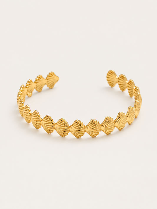 Gold scallop shell open cuff bracelet on a neutral background