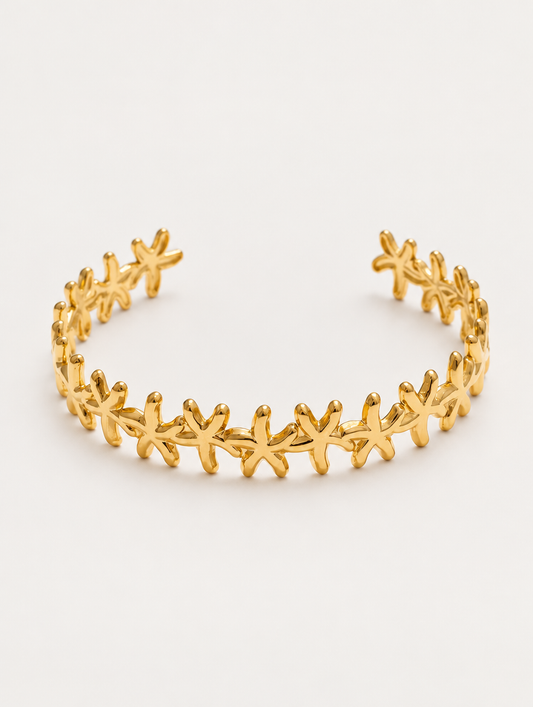 Gold starfish open cuff bracelet on a neutral background