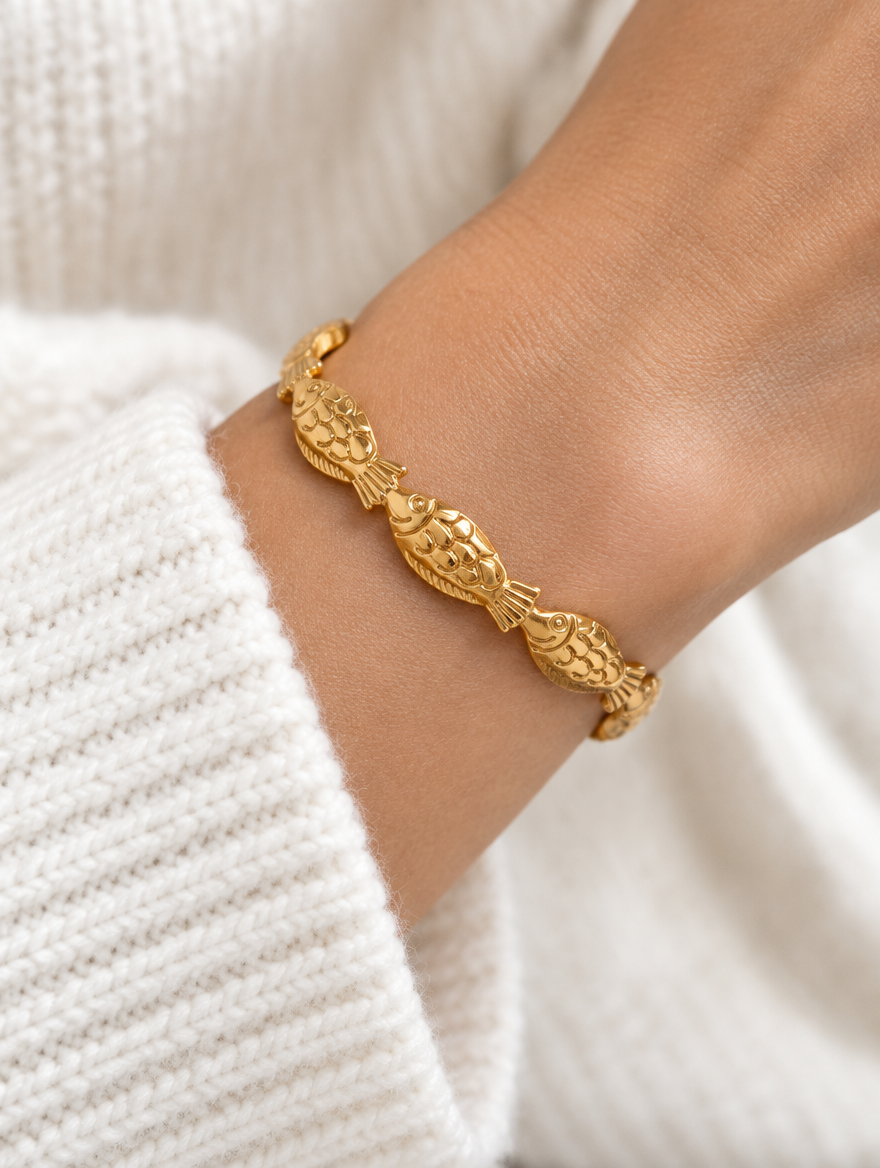 Woman wearing a gold fish open cuff bracelet