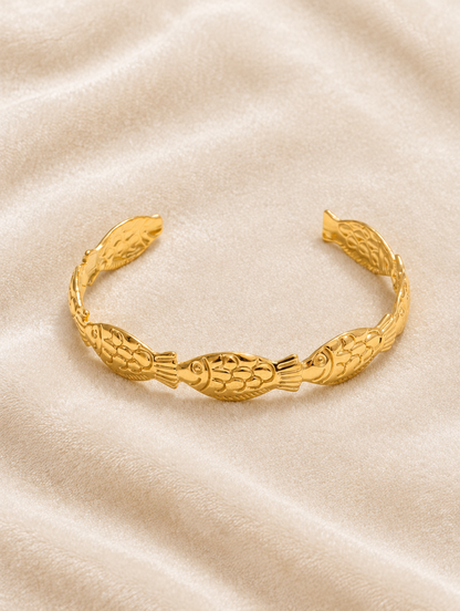 Gold fish cuff bracelet on cream velvet