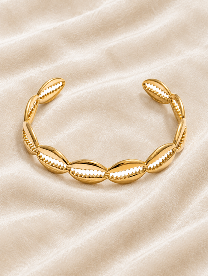 Gold hollow shell cuff bracelet on cream velvet