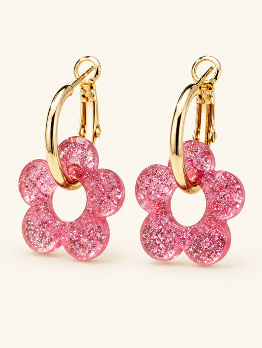 Pair of gold-tone flower huggie hoop earrings on a warm off-white background
