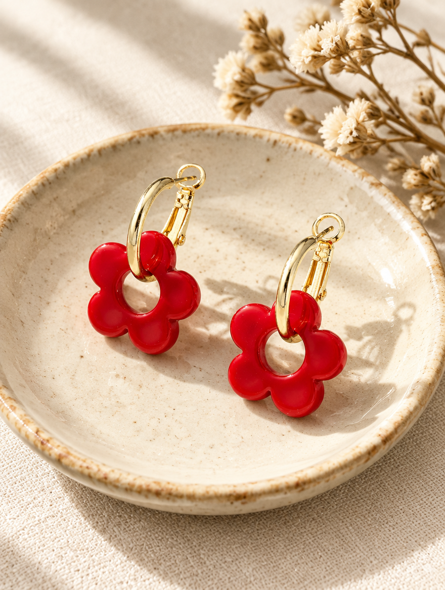 Gold-tone flower huggie hoop earrings in a styled still life with props