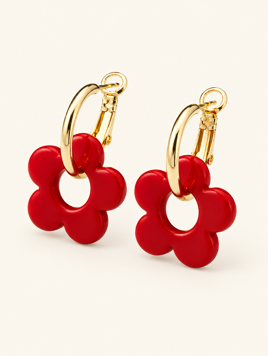 Pair of gold-tone flower huggie hoop earrings on a warm off-white background