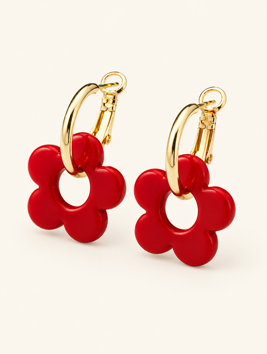 Pair of gold-tone flower huggie hoop earrings on a warm off-white background