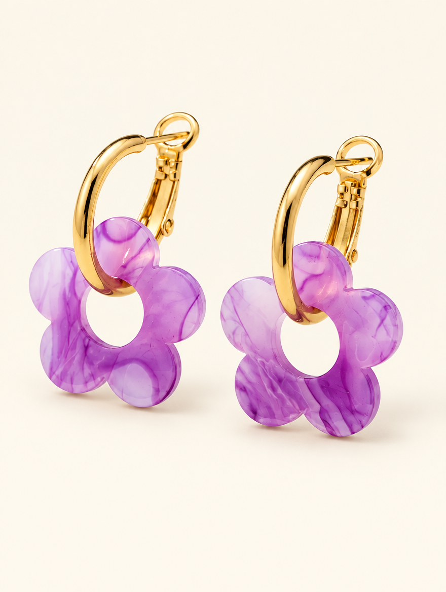 Pair of gold-tone flower huggie hoop earrings on a warm off-white background