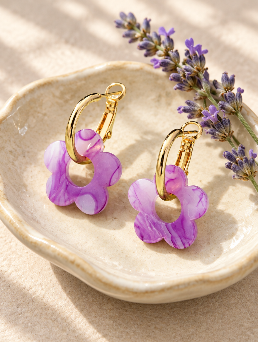 Gold-tone flower huggie hoop earrings in a styled still life with props