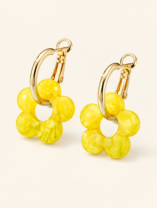 Pair of gold-tone flower huggie hoop earrings on a warm off-white background