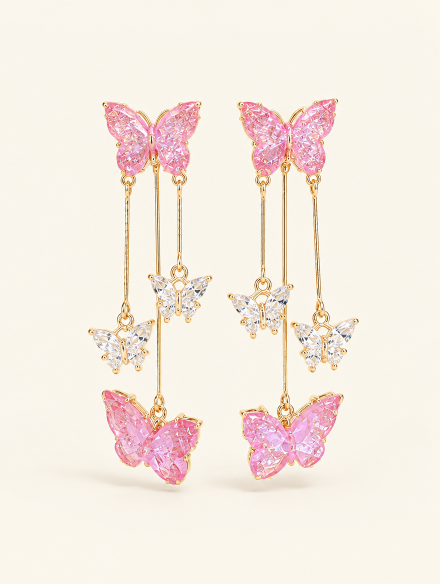 Pair of pink butterfly tassel drop earrings on a warm off-white background