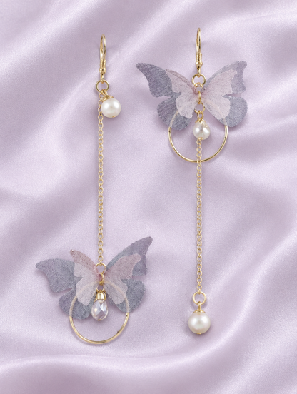 Lilac butterfly chain drop earrings lying flat on a soft styled surface