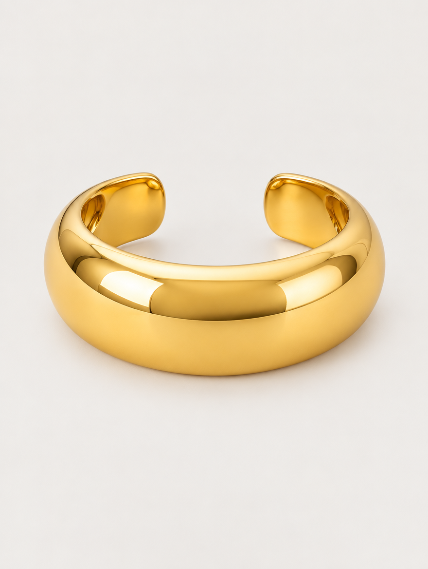 Chunky gold-tone domed open bangle on a neutral background