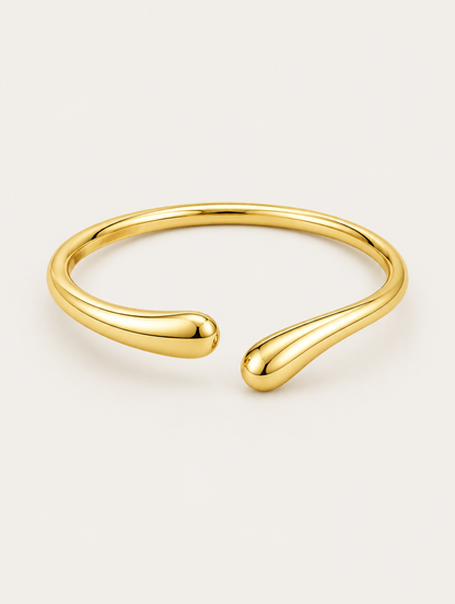Slim gold-tone teardrop open cuff bracelet on a neutral background