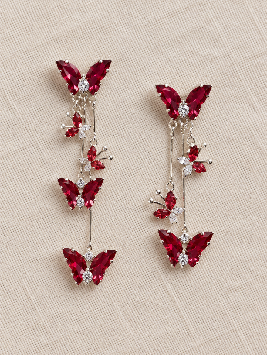 Red butterfly tassel drop earrings lying flat on a soft styled surface