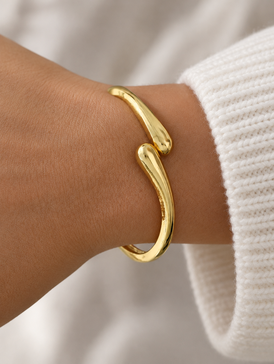 Woman wearing a slim gold-tone teardrop open cuff bracelet
