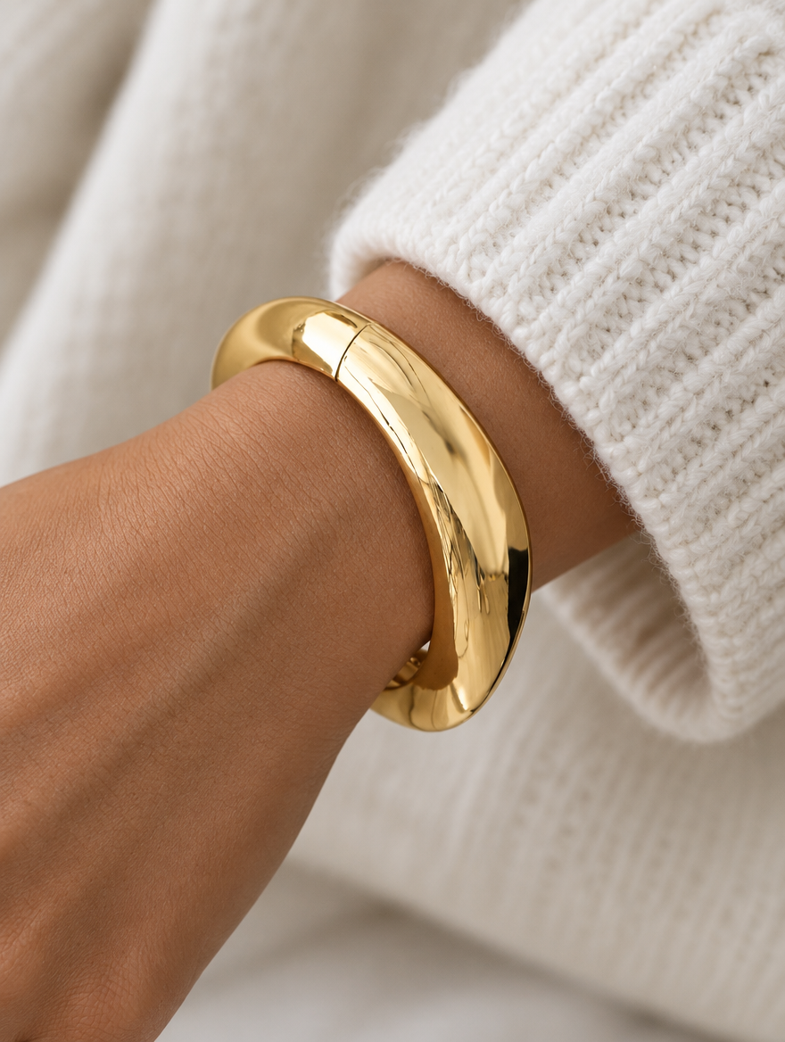Woman wearing a chunky gold-tone domed open bangle
