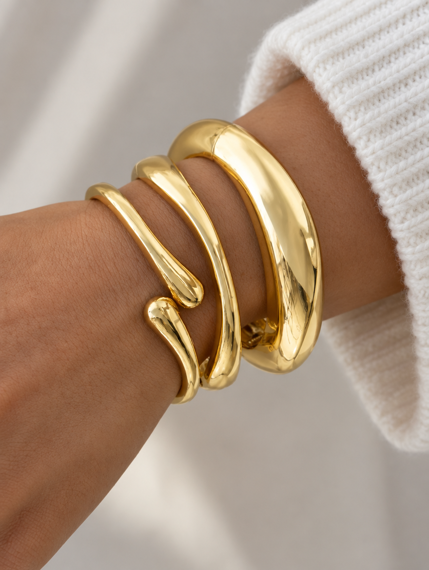 Woman wearing a stack of three gold-tone open bangles