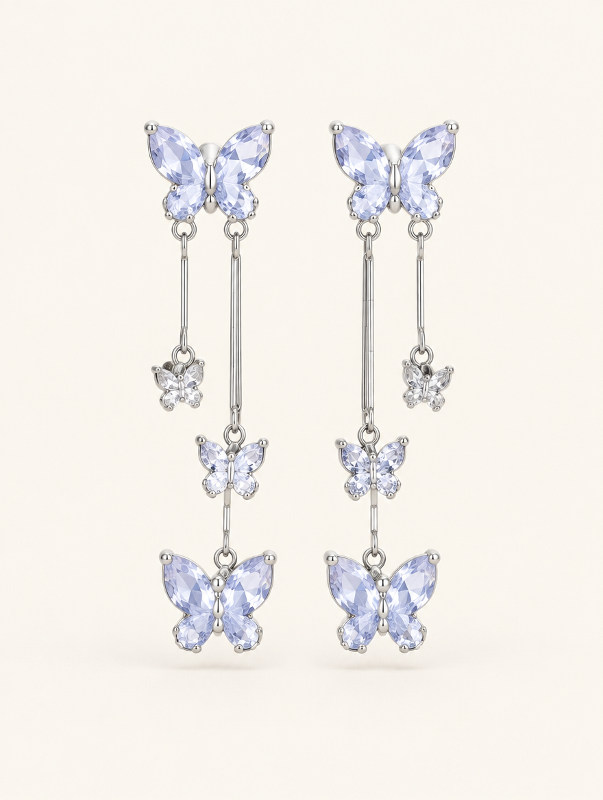 Pair of silver-lilac butterfly tassel drop earrings on a warm off-white background