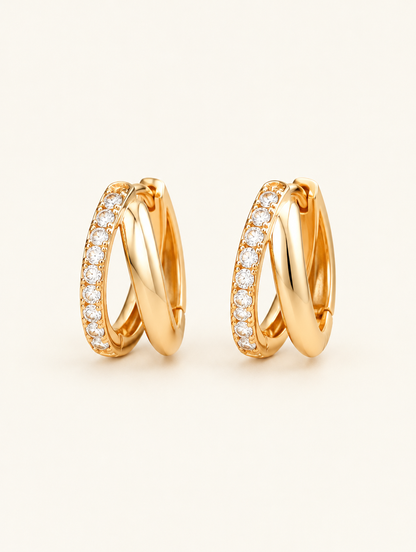 Pair of gold double-ring CZ huggie hoop earrings on a warm off-white background