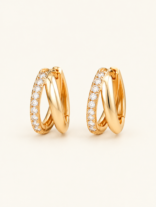 Pair of gold double-ring CZ huggie hoop earrings on a warm off-white background