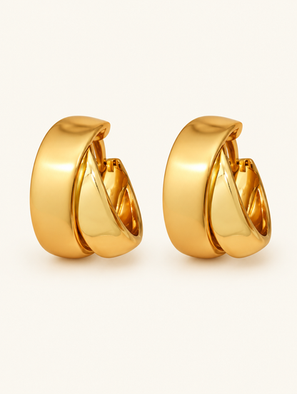Pair of chunky gold hoop earrings on a warm off-white background