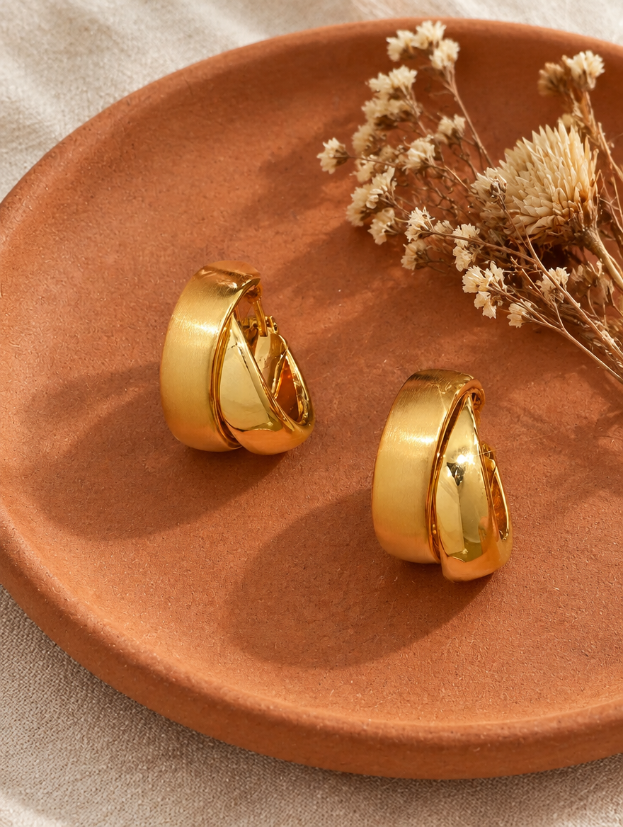 Chunky gold hoop earrings in a styled still life with props