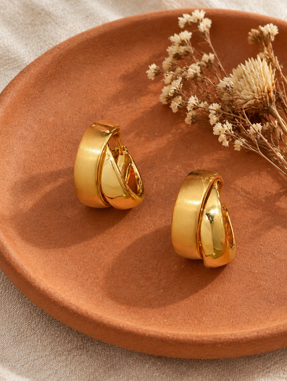 Chunky gold hoop earrings in a styled still life with props