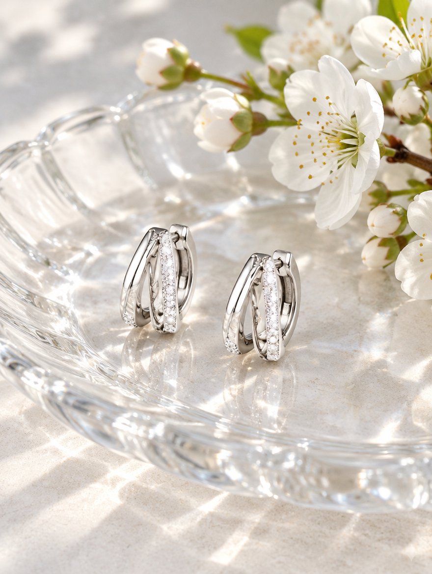 Silver double-ring CZ huggie hoop earrings in a styled still life with props