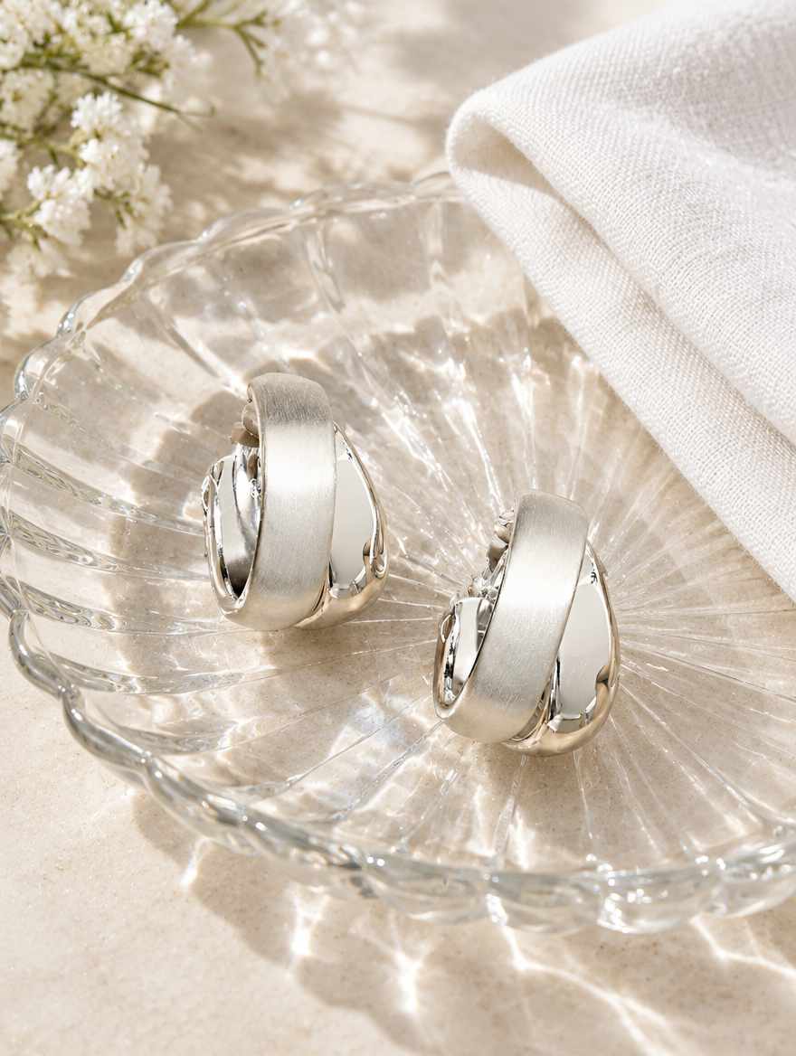 Chunky silver hoop earrings in a styled still life with props