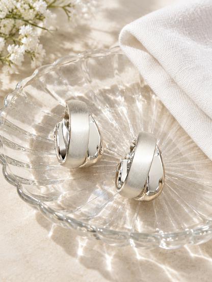 Chunky silver hoop earrings in a styled still life with props