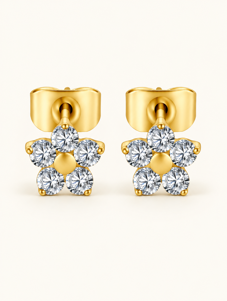 Pair of gold titanium CZ flower stud earrings on a warm off-white background