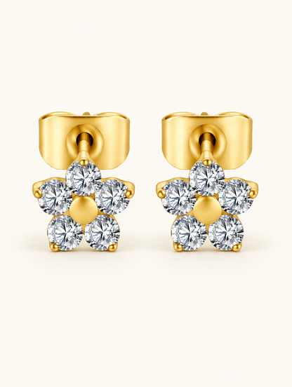 Pair of gold titanium CZ flower stud earrings on a warm off-white background