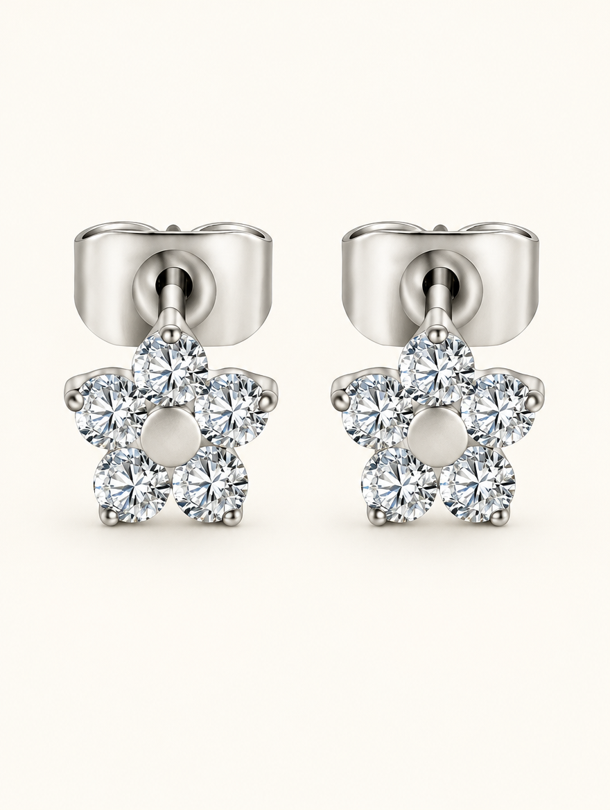 Pair of titanium CZ flower stud earrings on a warm off-white background