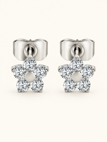 Pair of titanium CZ flower stud earrings on a warm off-white background