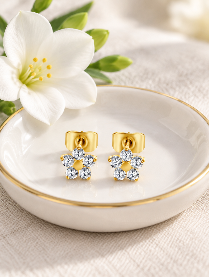 Gold titanium CZ flower stud earrings in a styled still life with props