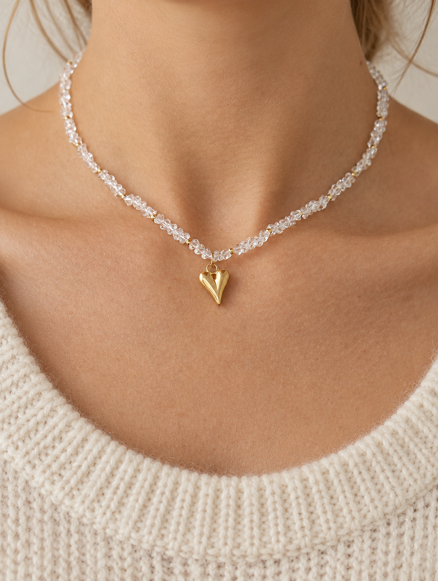 Woman wearing a clear bead choker necklace with a gold-tone heart pendant