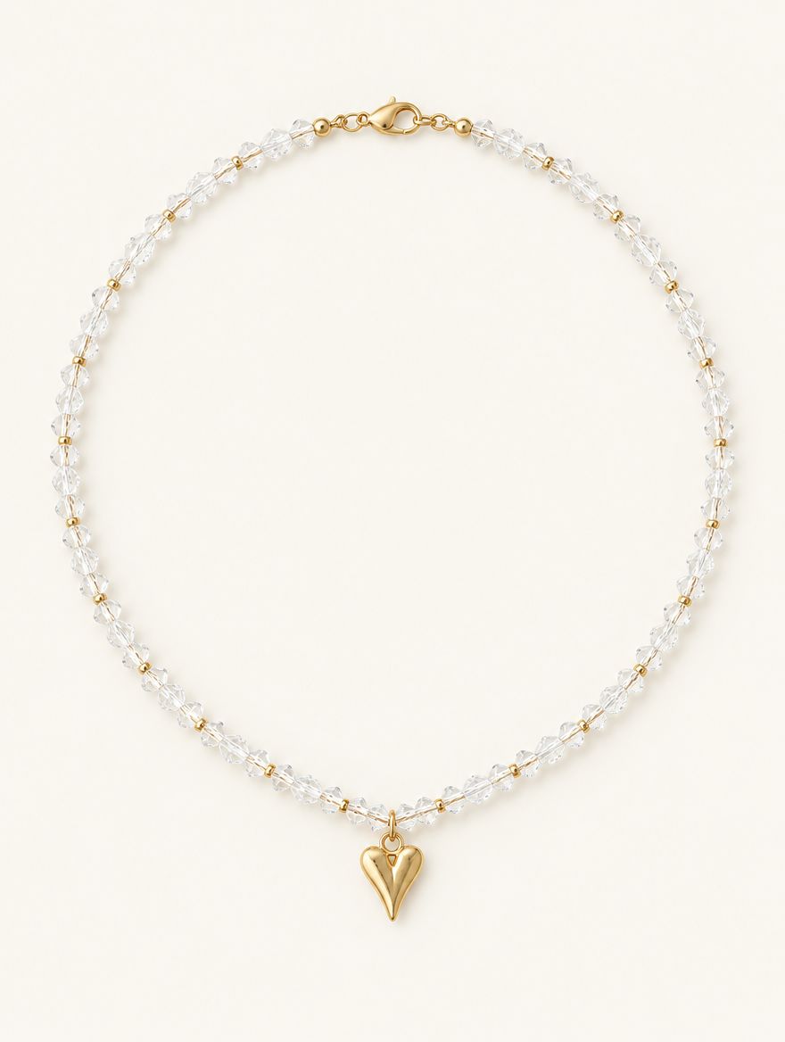 Clear bead choker necklace with a small gold-tone heart pendant on a neutral background
