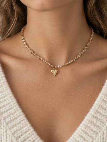 Woman wearing a champagne bead choker necklace with a gold-tone heart pendant