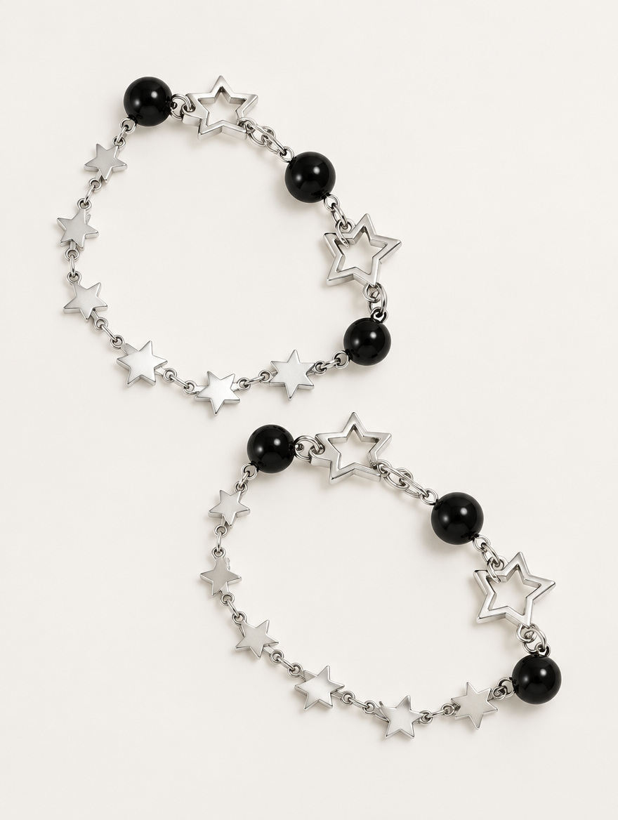 Silver-tone star chain bracelet set with black beads on a neutral background