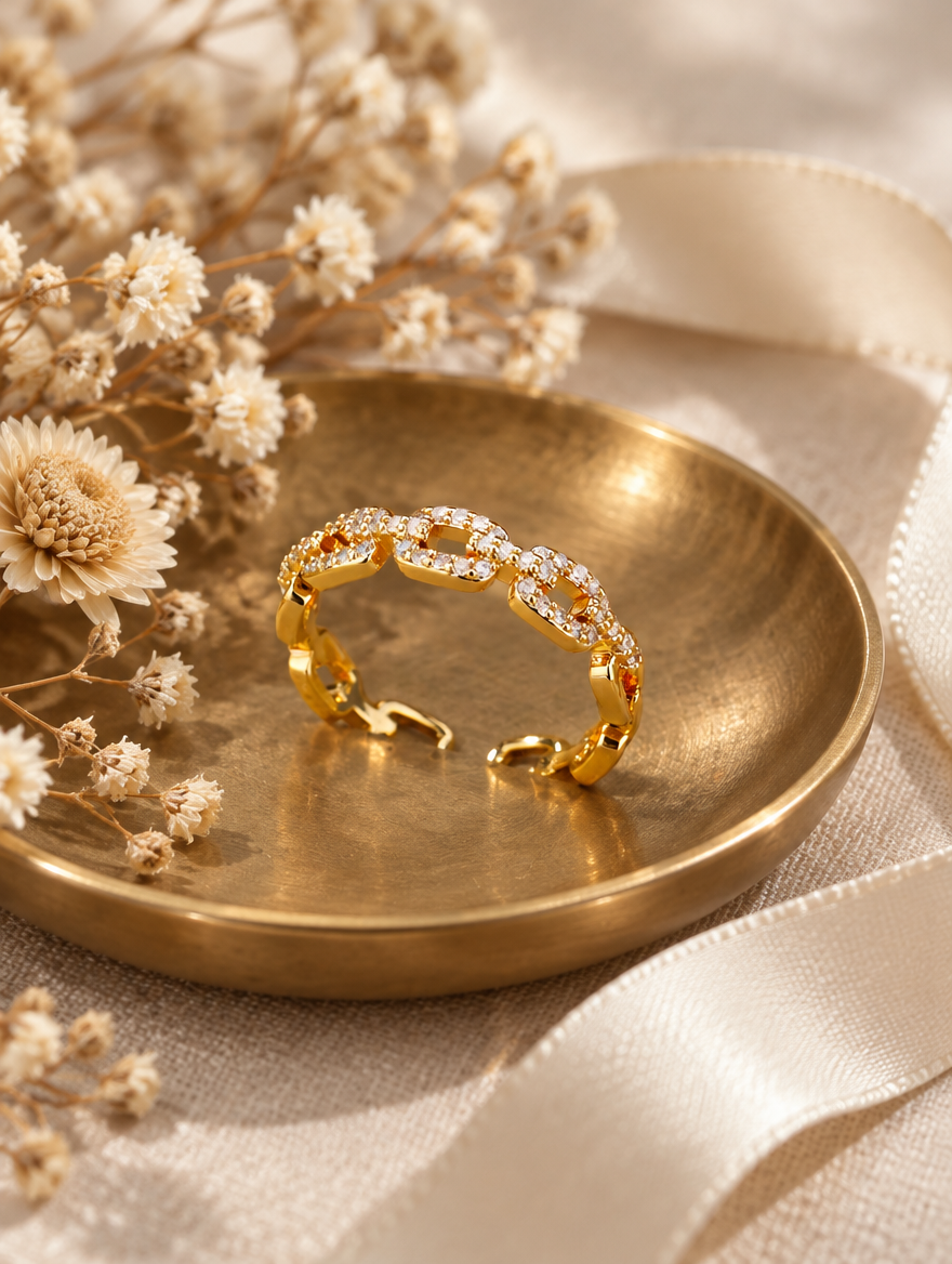 Gold slim chain link zirconia ring in a small dish with styling props