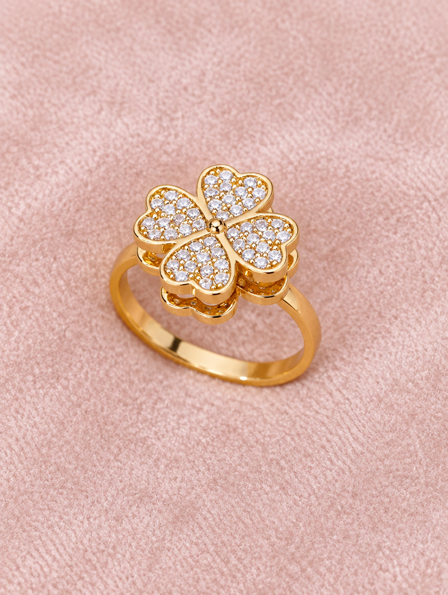 Gold four leaf clover zirconia ring resting on a soft textured surface