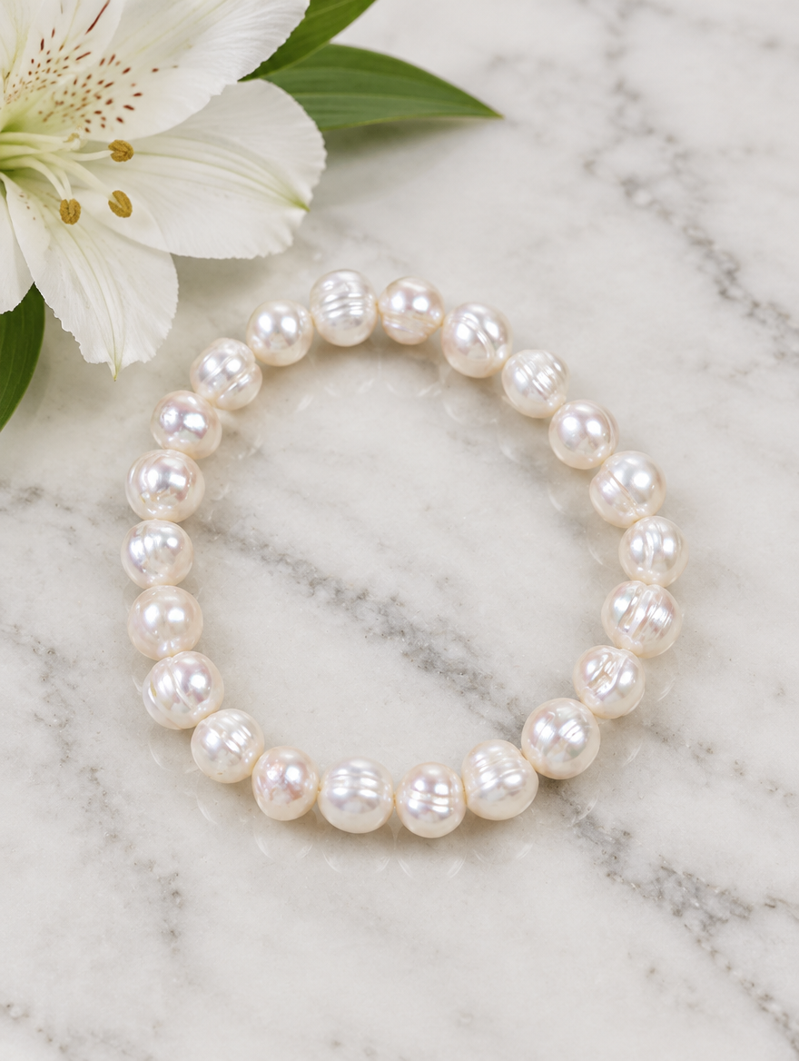 White pearl bracelet beside a white flower on marble