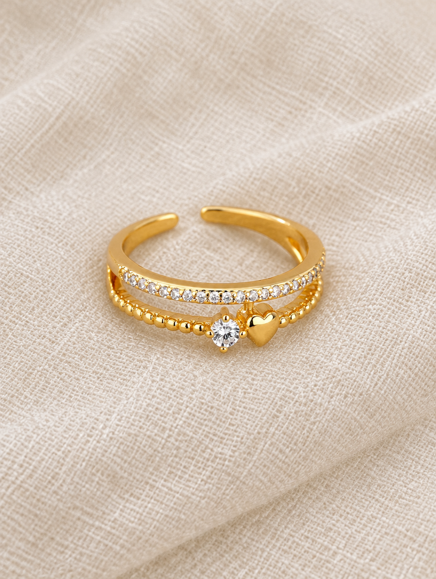 Gold double band heart zirconia ring resting on a soft textured surface