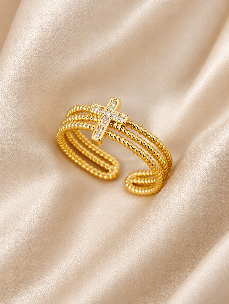 Gold ribbed triple band cross zirconia ring resting on a soft textured surface