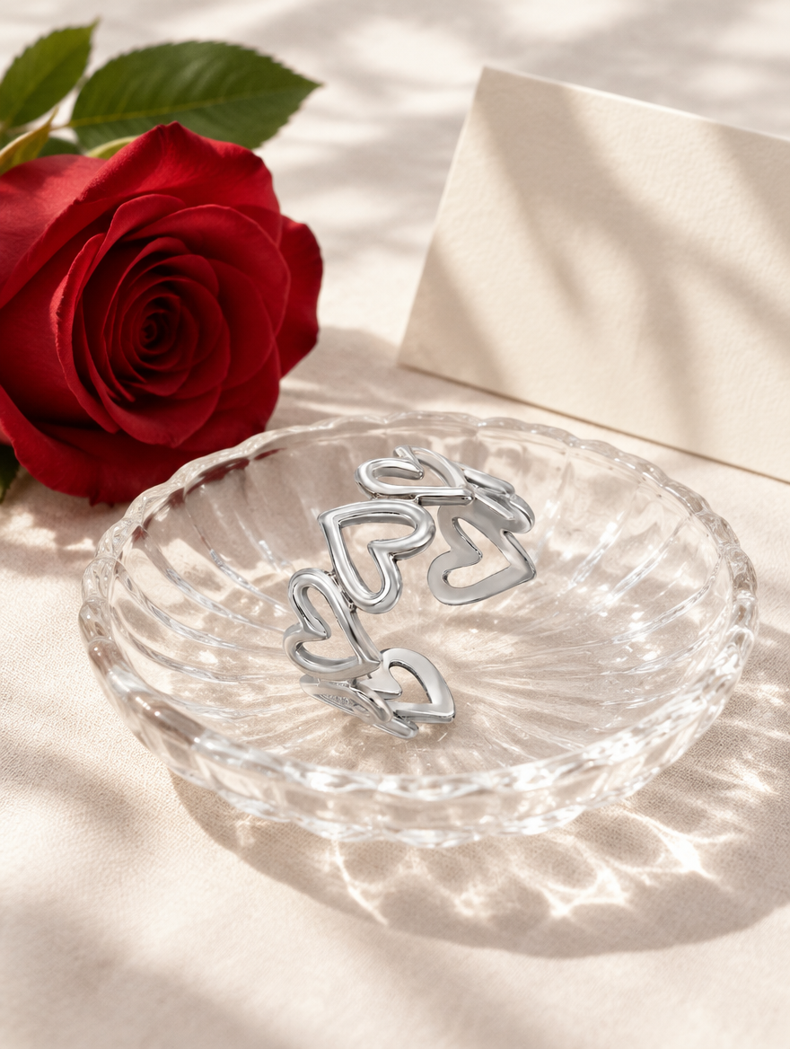 Silver hollow heart outline ring in a small dish with styling props