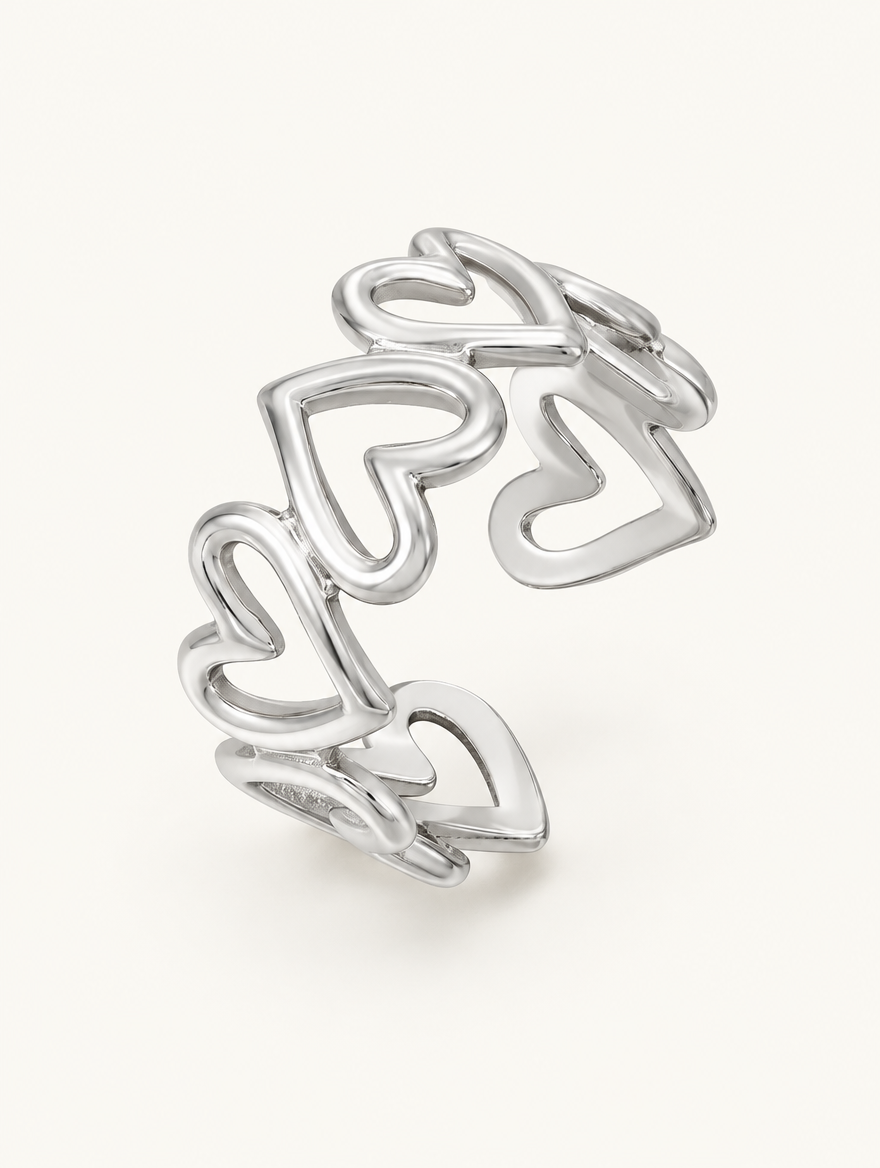 Silver hollow heart outline ring on a neutral background