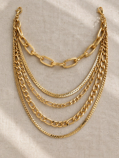 Gold layered chunky paperclip necklace stack laid flat on linen