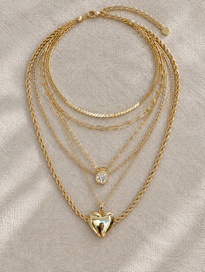 Gold layered heart pendant necklace stack laid flat on linen